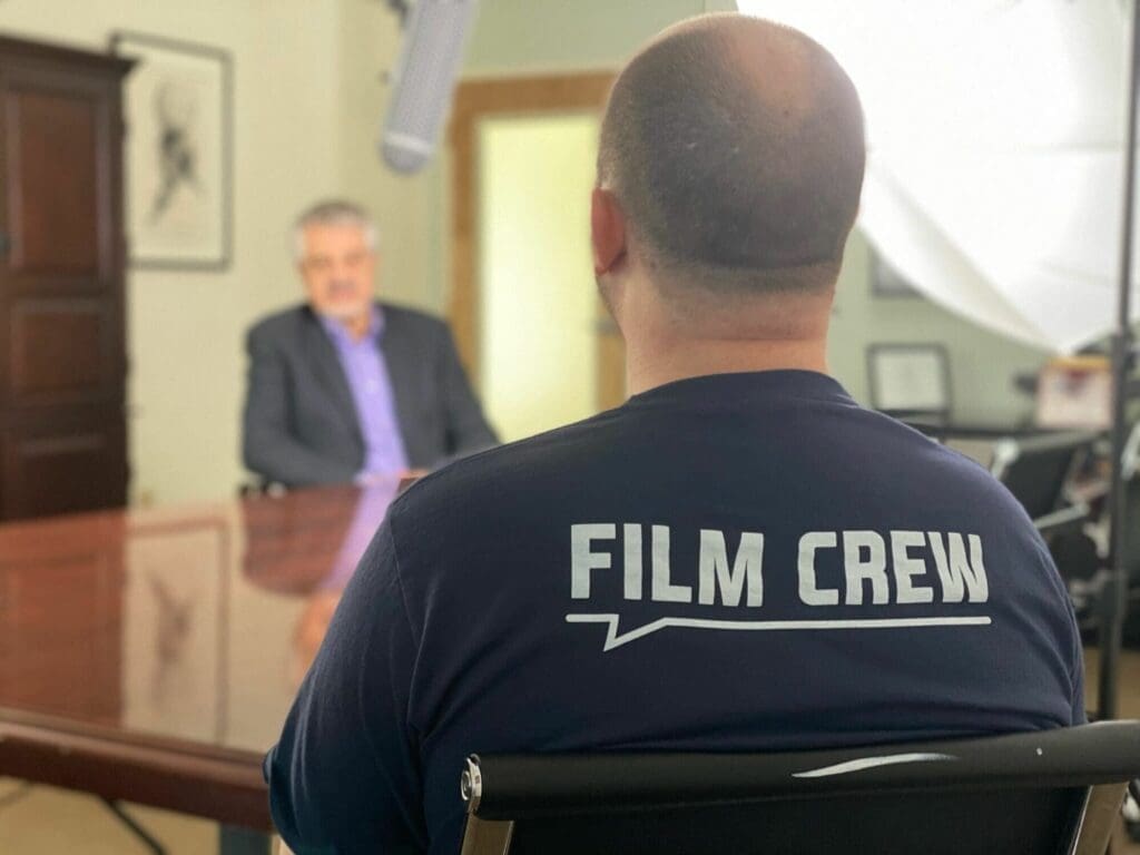A man in a chair wearing a film crew shirt.