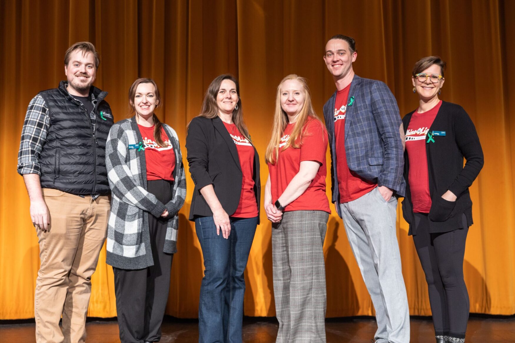 Group of six festival organizers on stage, smiling and standing together during a film festival.