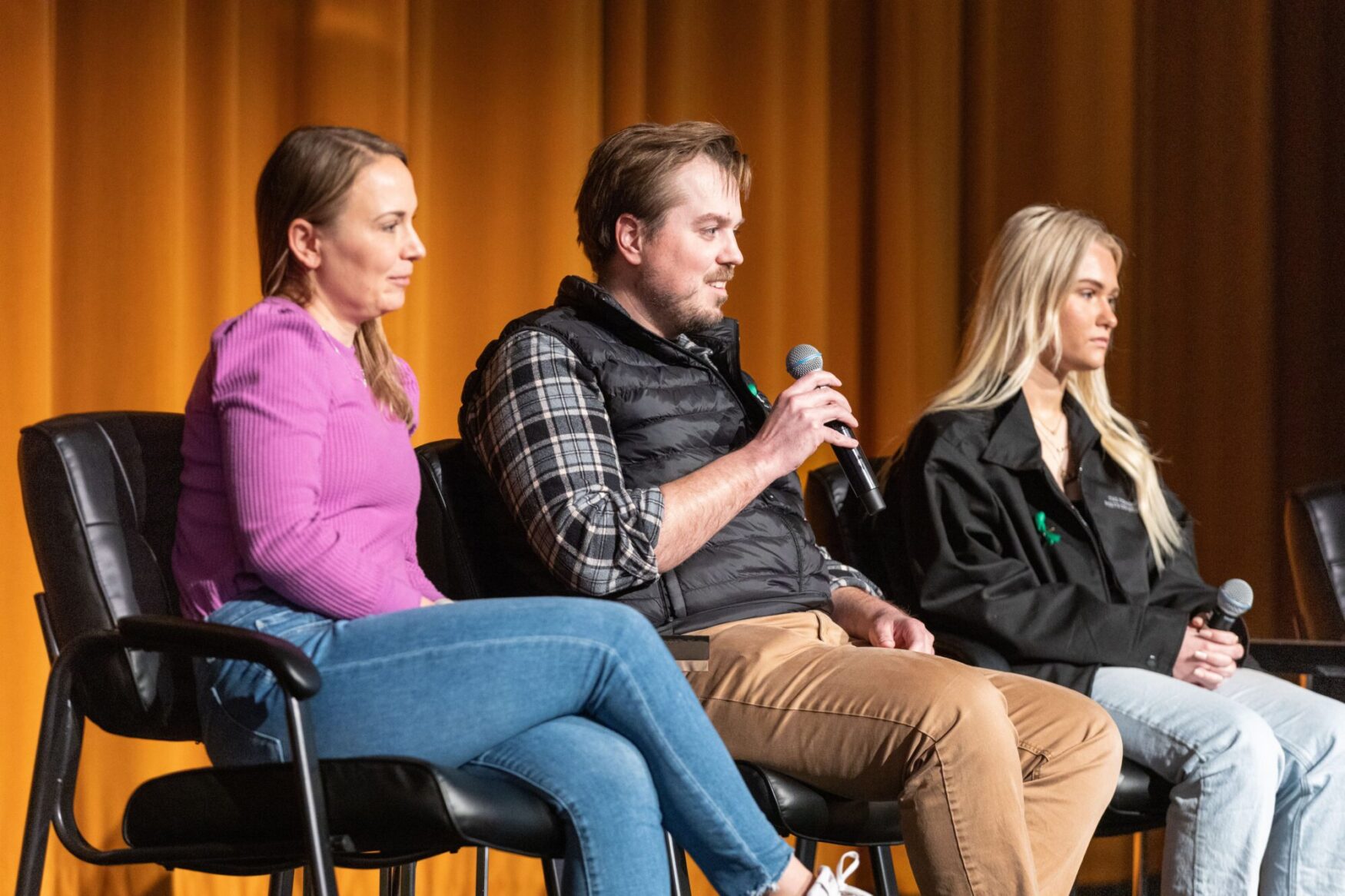 Three people sitting on a stage during a panel discussion at a film festival, with a man speaking into a microphone.