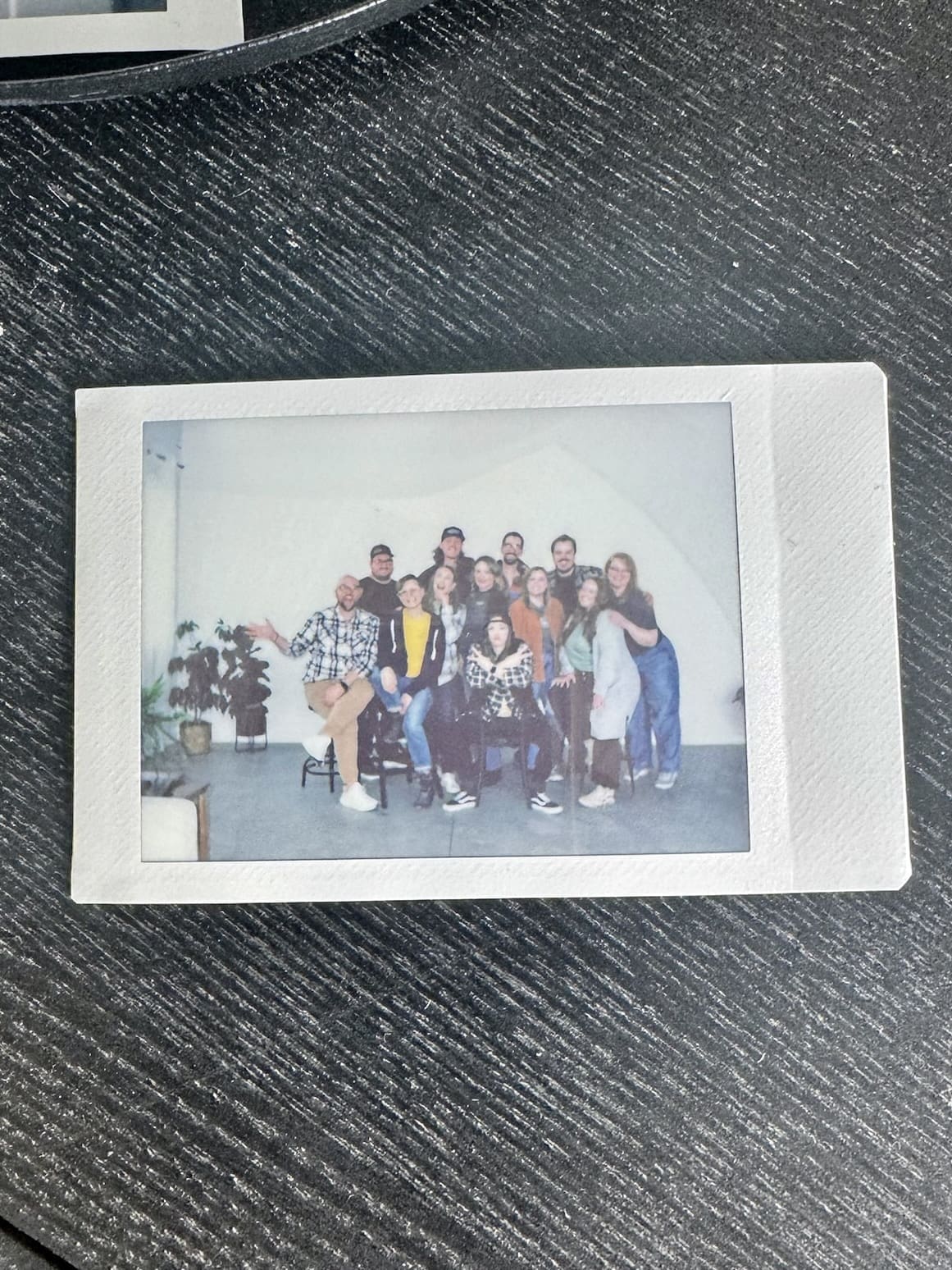 Group photo of a diverse team seated and standing in a bright room, smiling at the camera, with a casual and friendly atmosphere.