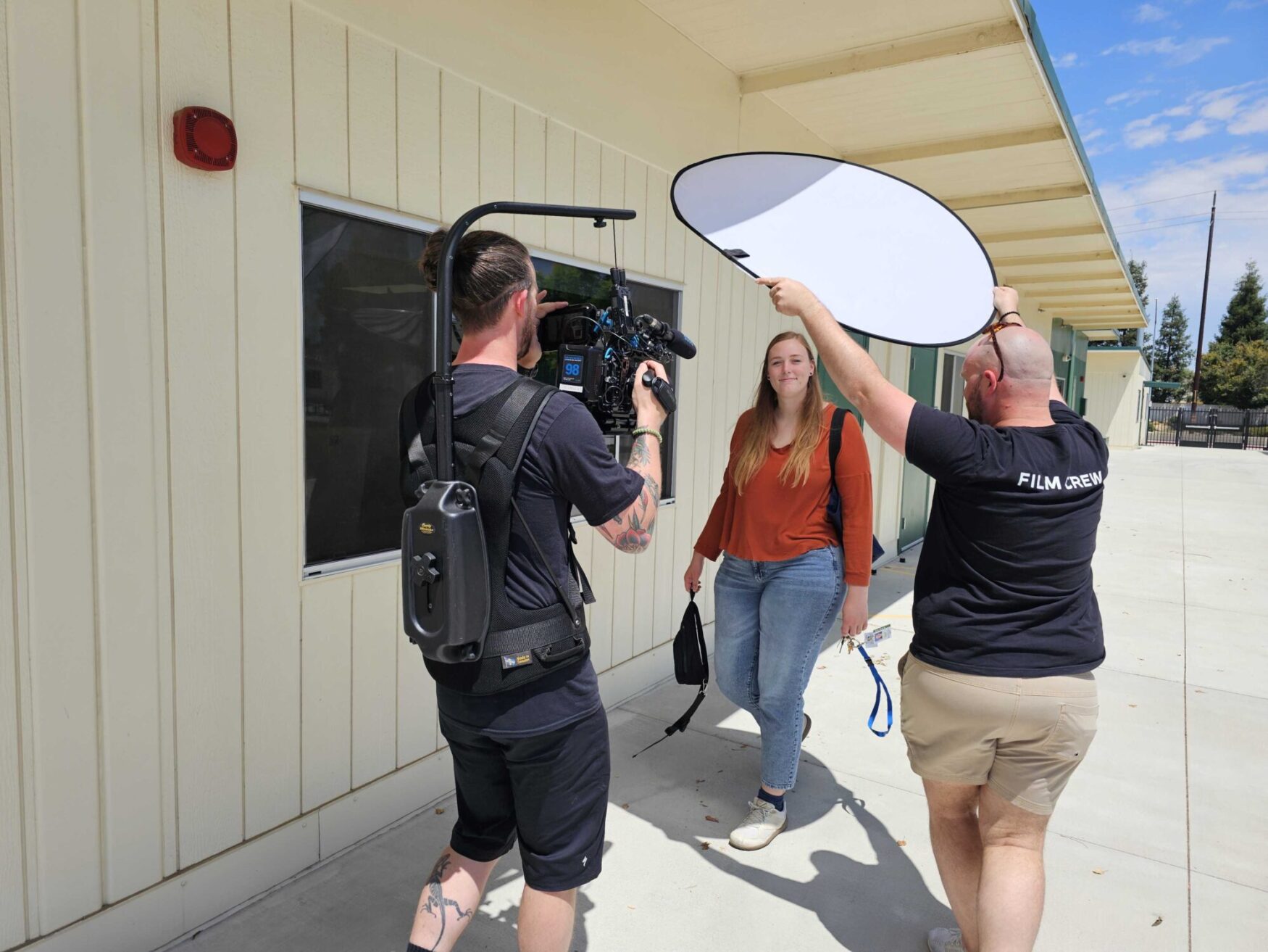 Duncan and Max filming a woman walking. She is calm and slightly smiling.