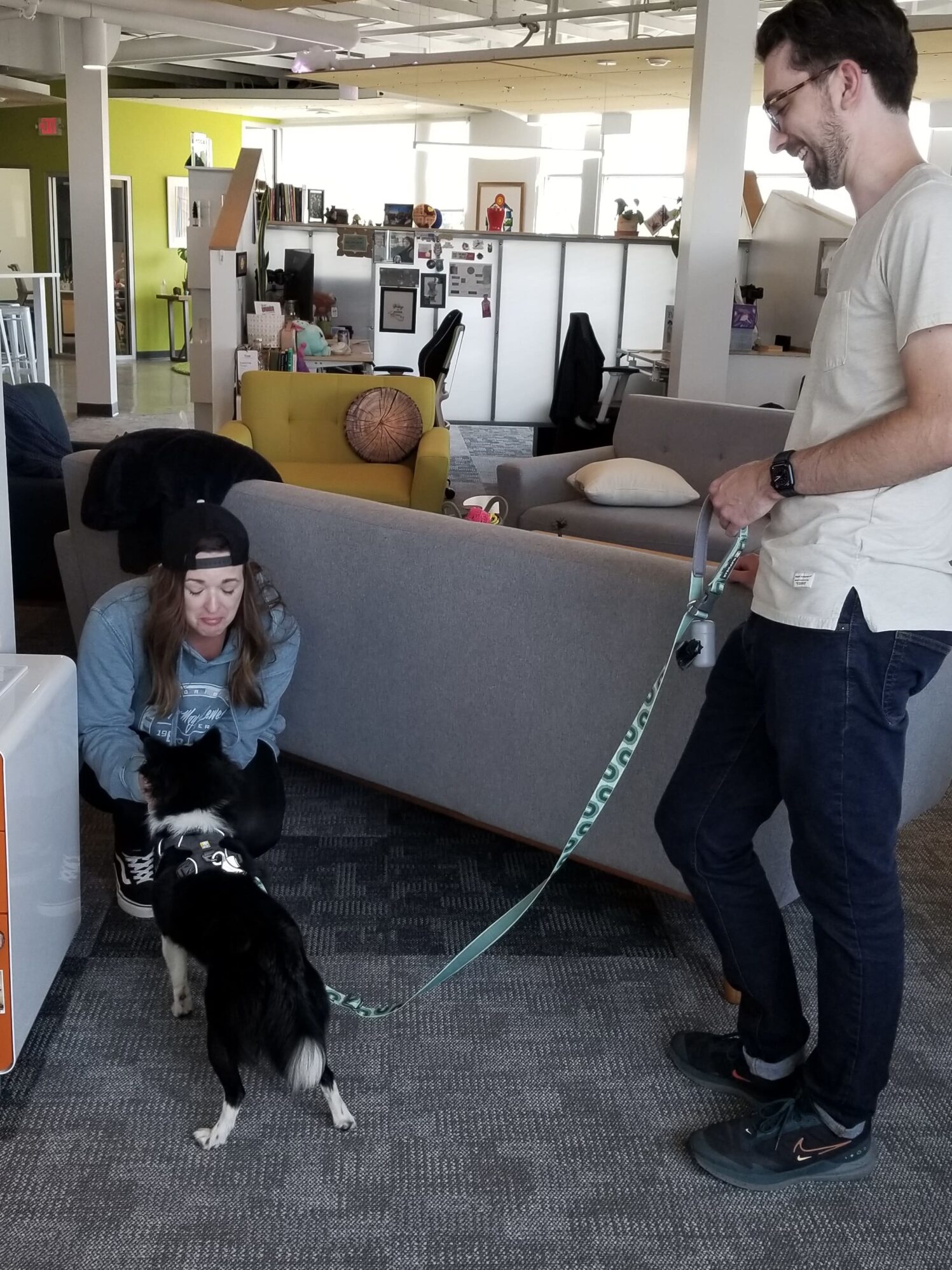 Sandie greets Dipper, a black and white dog, as Lucas holds Dipper's leash.