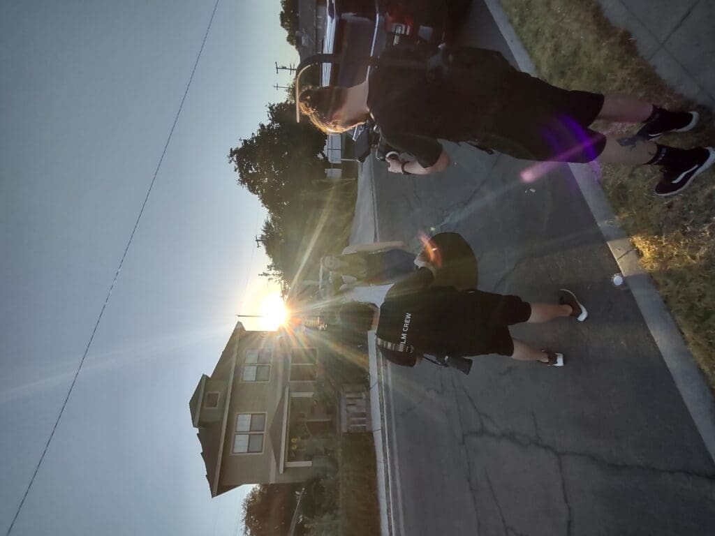 Sunlight streams past a house as Jordan and Duncan film a woman.