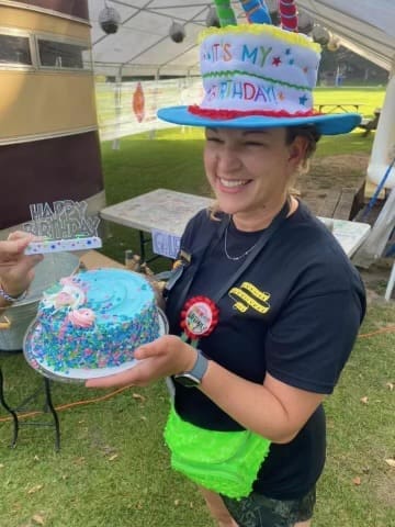 Annie, in a birthday cake hat, holds her birthday cake.