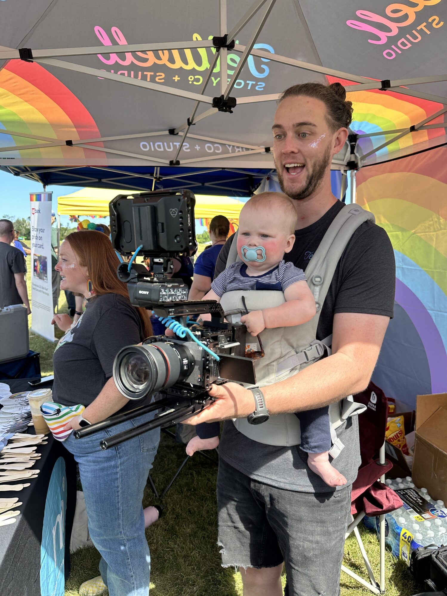 Dunan shows Oliver (strapped to his chest in a toddler holder) how to work a camera