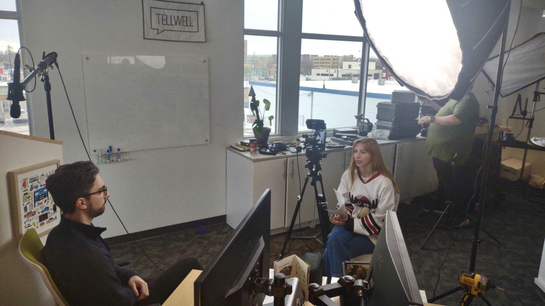 A man is being interviewed by a woman in a friendly office setting.