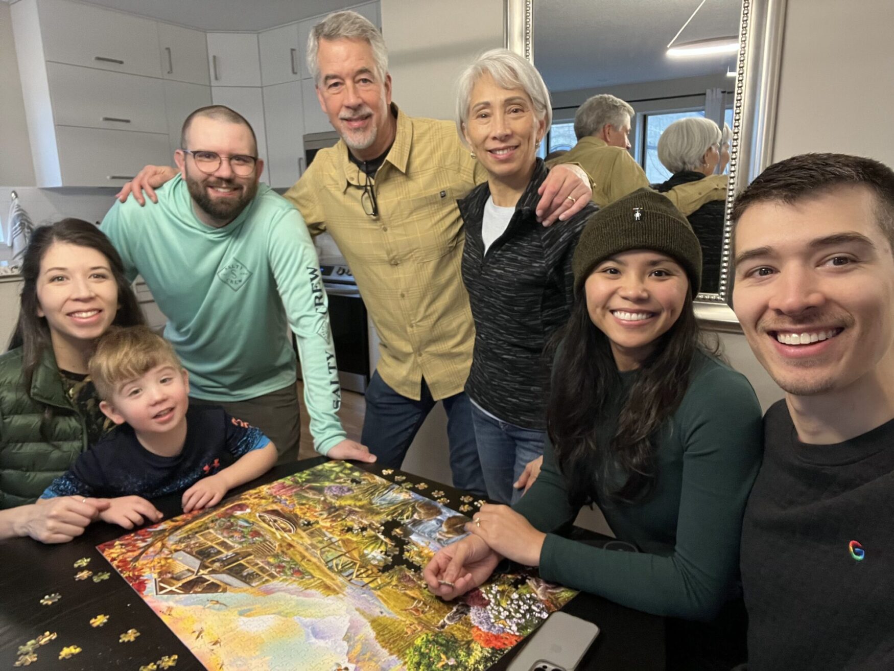 A group of people gathered around a table with a completed jigsaw puzzle.