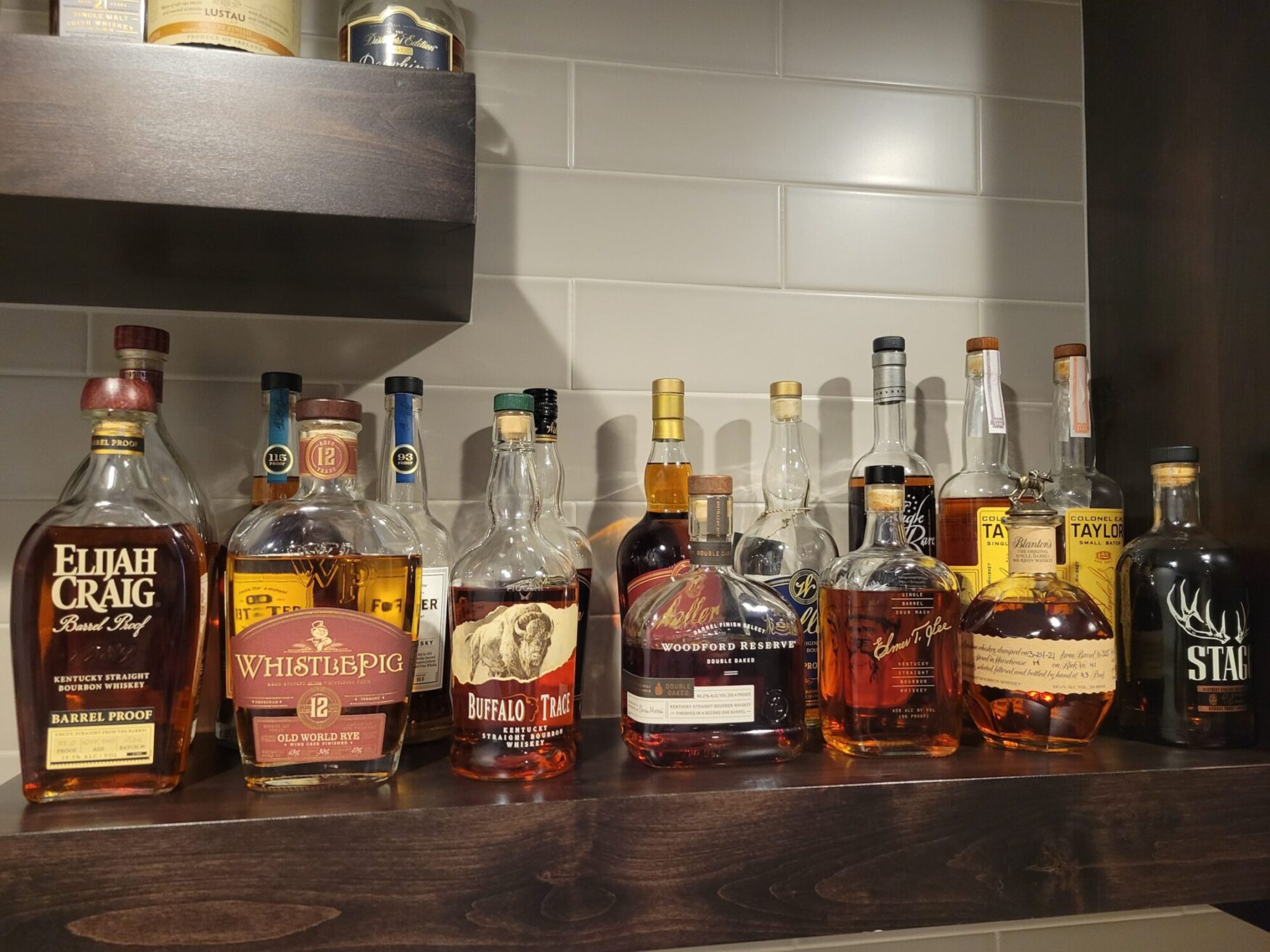Several whiskey bottles lined up on a wooden shelf.
