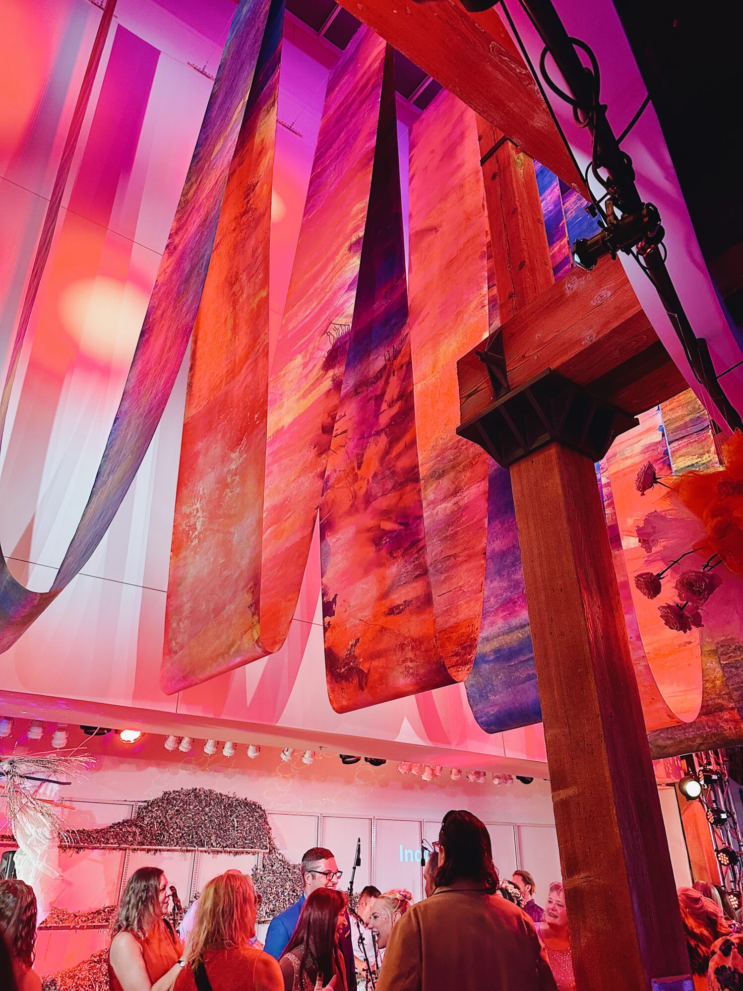 An abstract piece of art hangs from the ceiling. A crowd gathers below.