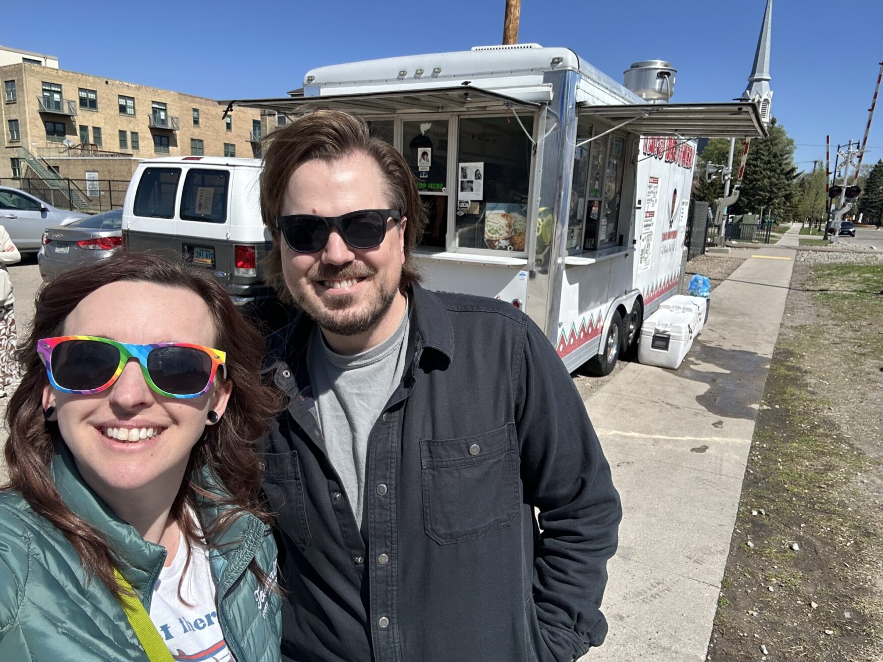 Three individuals stand in front of a food truck.