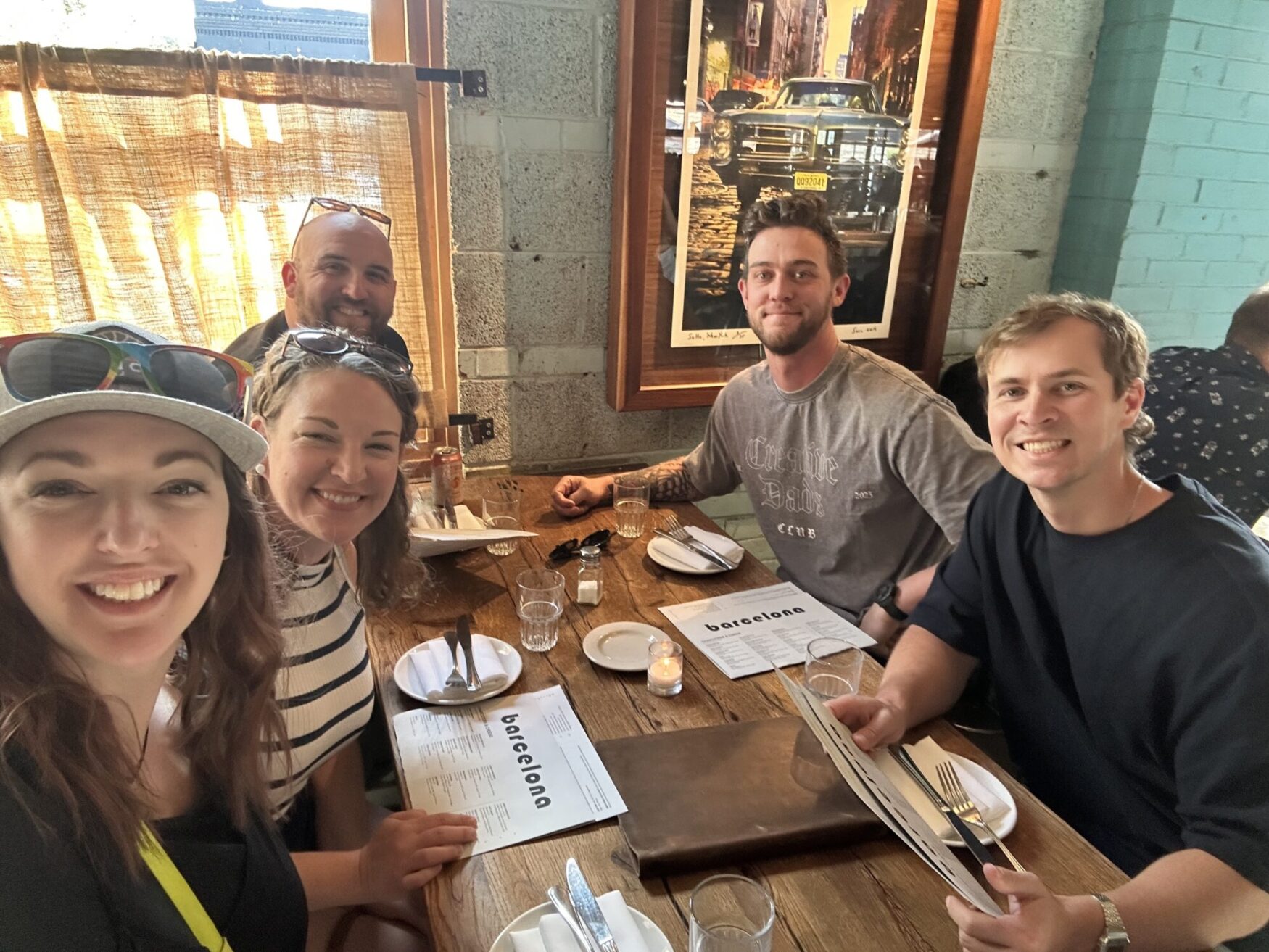Two women and three men smile for a photo while sitting at a dinner table in a restaurant. The atmosphere is cozy and friendly.