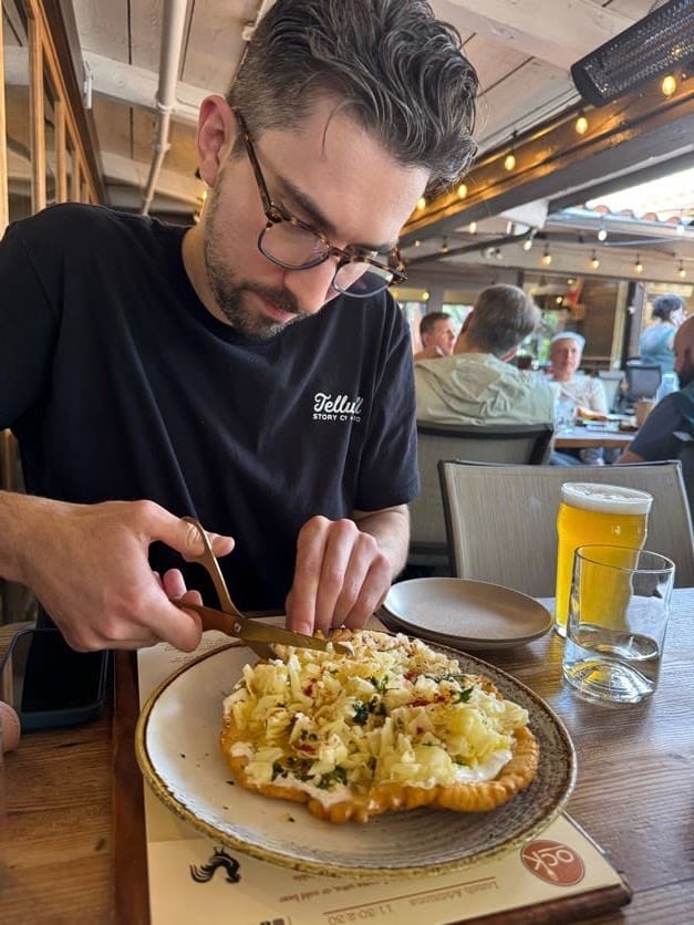A man cuts what looks like a pizza with scissors.