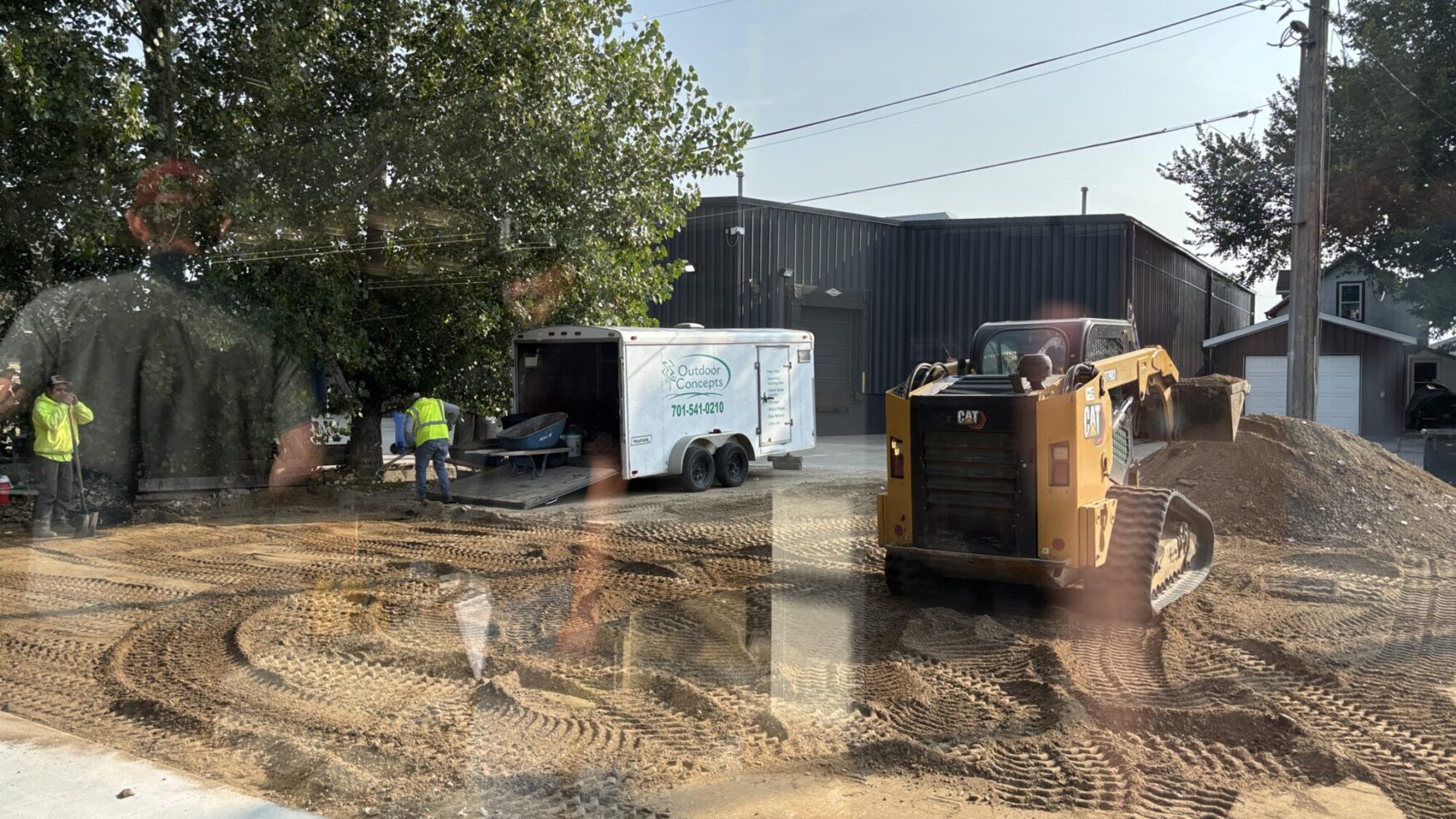 A construction crew working outside with a yellow skid steer and dirt piles, preparing the area near Tellwell’s new office.