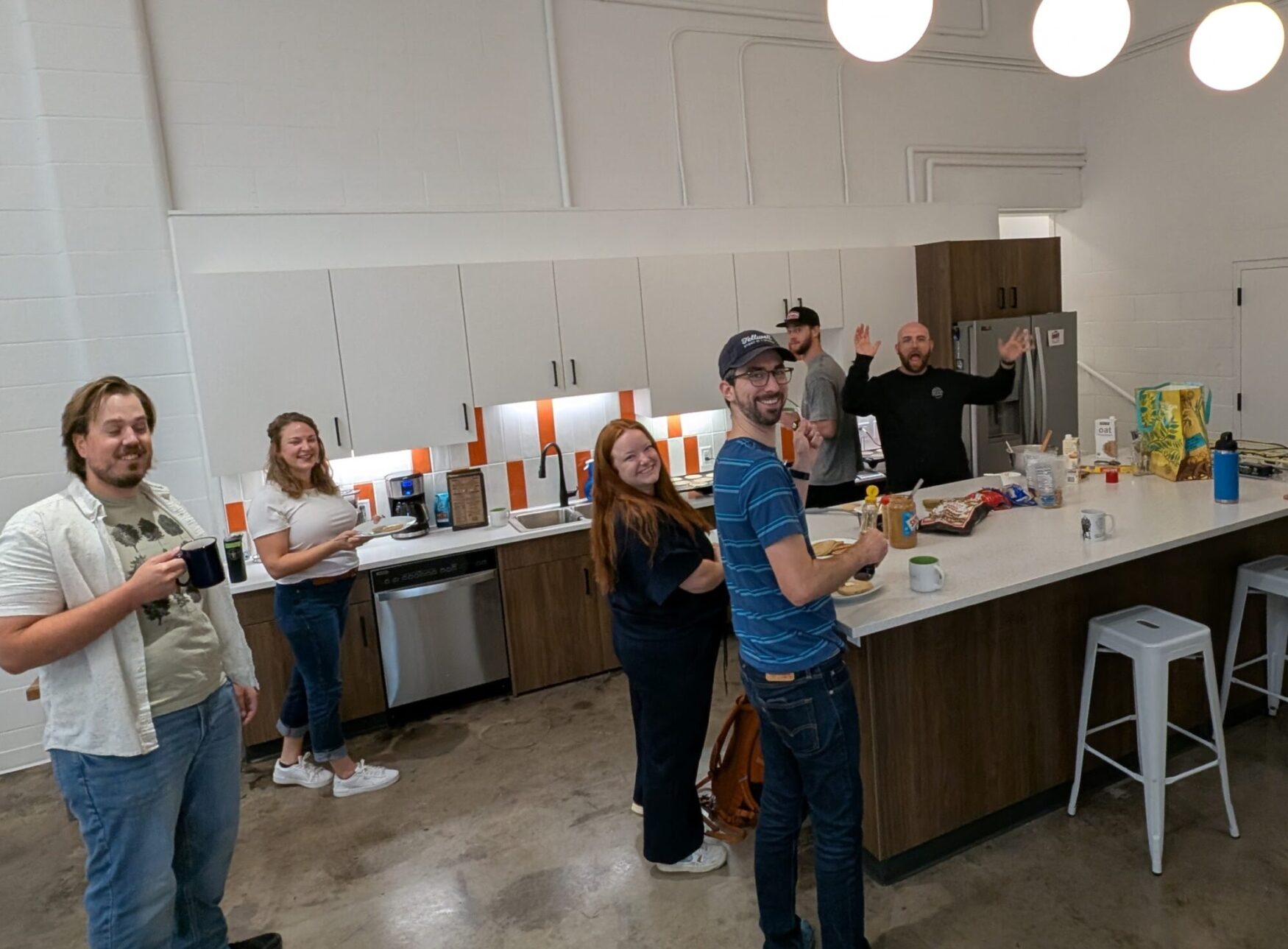 Tellwell team members gathered in the bright office kitchen, smiling and serving up breakfast together.